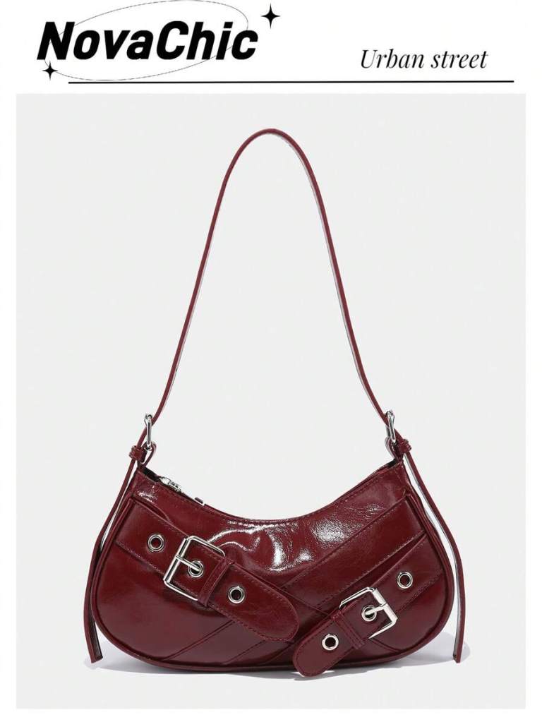 A stylish burgundy handbag featuring a curved design, silver buckles, and a shoulder strap, set against a light gray background.